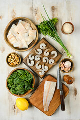 Fresh seafood and vegetables arranged on a wooden table for meal preparation in a bright kitchen