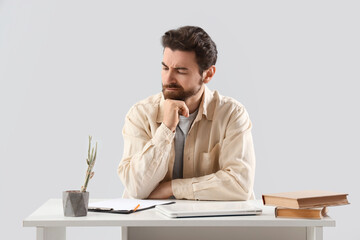 Portrait of worried man at table on light background