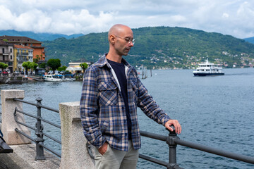 Young traveler man relaxing on Baveno promenade, man enjoying Marjorie lake view, summer breeze, peaceful moment, solo trip, scenic destination