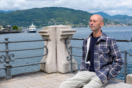 Young traveler man relaxing on Baveno promenade, man enjoying Marjorie lake view, summer breeze, peaceful moment, solo trip, scenic destination - Powered by Adobe