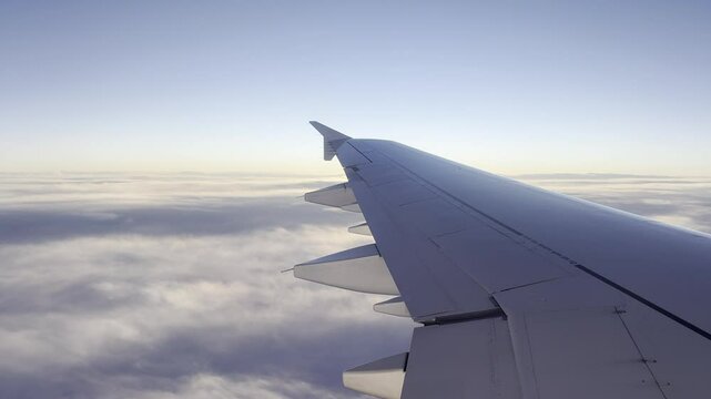 Blick aus einem Flugzeug &uuml;ber weitreichende Wolkenlandschaften mit einem blauen Himmel im Hintergrund