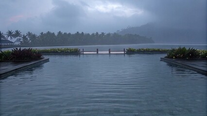 Where the still pool meets the misty horizon in a tropical embrace.