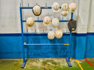 Industrial Safety Helmets on Blue Rack in Factory Workplace