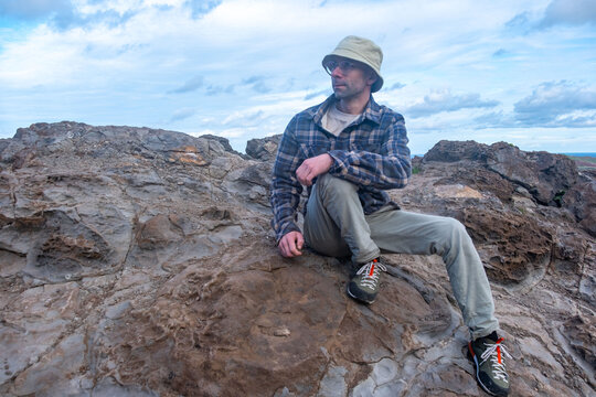 young traveler man sits on volcanic rocks, enjoying breathtaking landscape volcanic Madeira Island during journey, Viewpoint Calhau da Furna do Bode, discovery archipelago travel, adventure vacation