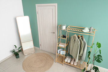 Interior of stylish hallway with clothes rack, mirror and door