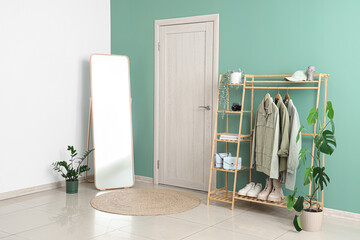 Interior of stylish hallway with clothes rack, mirror and door
