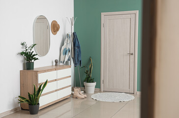 Interior of stylish hallway with door, clothes rack and mirror