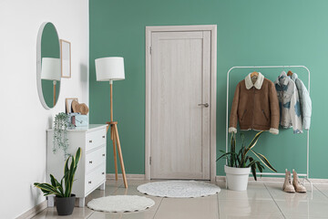 Interior of stylish hallway with door, lamp and coat rack