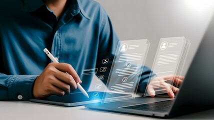 A businessman uses a stylus and laptop to review candidate resumes on a digital interface, emphasizing the recruitment process