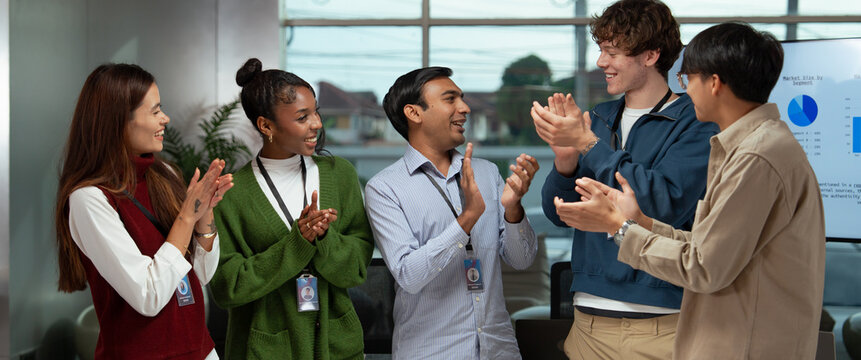 Diverse office business team meeting celebrating success with smiling colleagues clapping hands in modern workspace creating positive and energetic atmosphere
