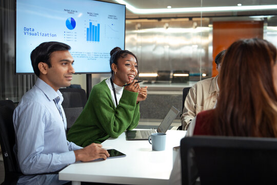 Diverse office business team meeting discussing data visualization with laptop tablet and coffee cup in modern workspace showing collaboration and engagement