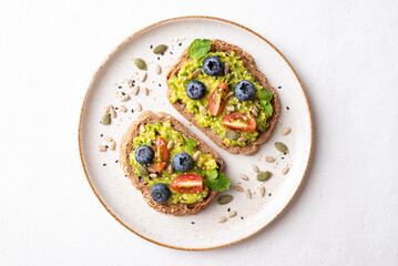 Avocado toast with blueberries, cherry tomatoes, sunflower seeds, pumpkin seeds, sesame seeds and other grain on plate, Healthy eating