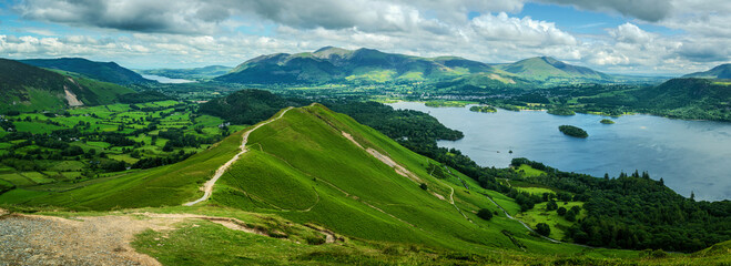 A panoramic view from the summit of Catbells reveals the ascending ridgeline stretching below...