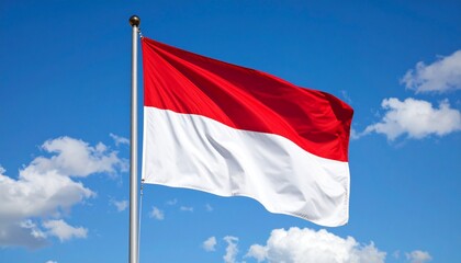 Indonesian national flag waving proudly against a vibrant blue sky with scattered clouds