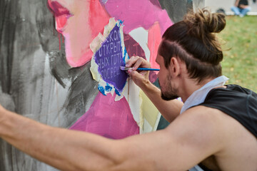 Young adult male artist painting vibrant mural outdoors. Focused expression, natural light...
