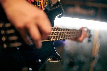 Focused view of musician hand playing bass guitar during performance, highlighting strings and...
