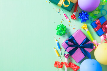 Happy birthday flat lay with presents, balloons, and candles on a mint green surface