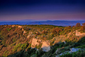 Early morning landscape from the top of Mount Alaric in the South of France. Garrigue, rocks, horizon, and the snow-capped Pyrenees.