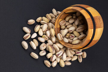 Heap of tasty pistachio nuts in the bowl on dark background