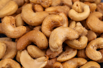Top view of Roasted cashew nuts in glass bowl on dark background.