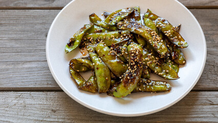 Asian Sugar Snap Peas dish. Pea pods stir-fried with garlic, ginger, and soy sauce, and sprinkled...