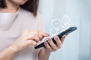 Close up of woman’s hand using mobile phone with AI chatbot, ChatGPT, and smart assistant app for...