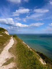 Trail along the White Cliffs of Dover with the sea in the background. Green meadows and classic English countryside paths. Concept of rural tourism, hiking, and exploring the scenic coast of England