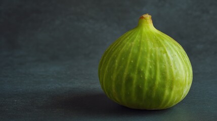 Obraz premium Single fresh green fig with vibrant texture against dark mottled surface