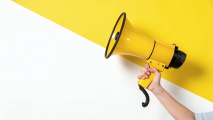 Hand holding yellow megaphone against diagonally split yellow and white background symbolizing expression, announcement, and public communication.