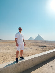 Tourist standing at giza pyramids plateau with clear sky background