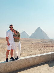 Tourists couple embracing with giza pyramids in background, cairo, egypt