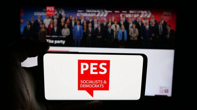 Stuttgart, Germany - 06-27-2025: Person holding cellphone with logo of Party of European Socialists (PES) on screen in front of webpage. Focus on phone display.