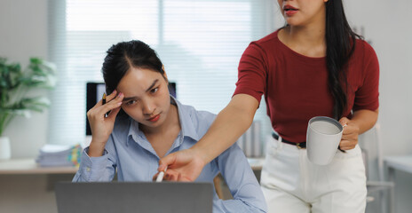 Manager assisting a stressed employee having problems with her laptop at work
