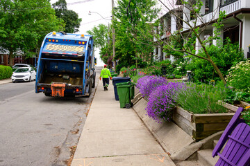 green economy: municipal garbage truck and worker with high visiblity safety clothing on a...