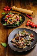 The first plate features a colorful Asian-style stir-fried vegetable salad topped with sesame seeds, while the second offers tender grilled chicken in a creamy sauce with sesame seeds and vegetables