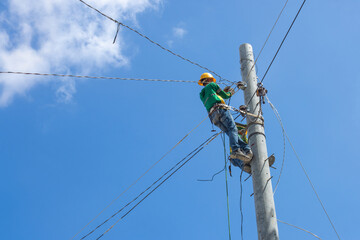 a team of electricians installs high-voltage electrical wires on poles