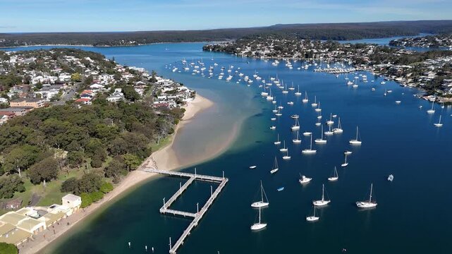 Drone establishing overview of Gunnamatta Bay with boats anchored and houses along the curved shoreline, Sydney NSW Australia