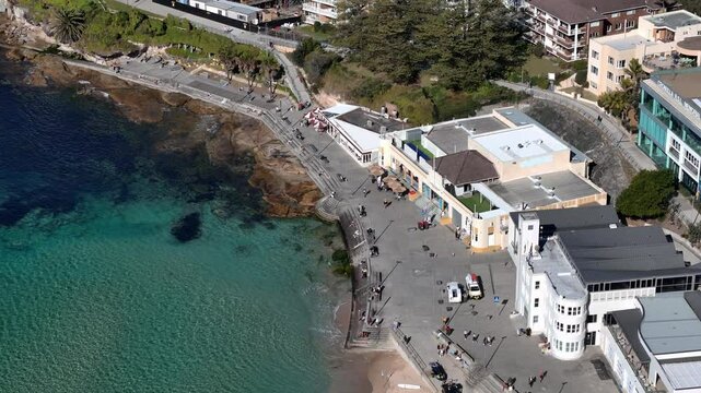 Drone of Cronulla headland, coastline, buildings and blue sea under clear sky, establishing of promenade, Sydney NSW Australia