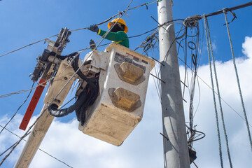 a team of electricians installs high-voltage electrical wires on poles