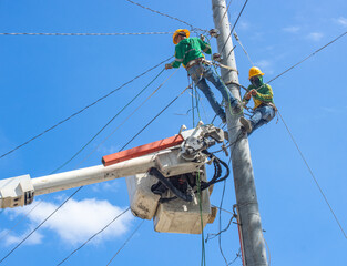 a team of electricians installs high-voltage electrical wires on poles