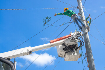 a team of electricians installs high-voltage electrical wires on poles