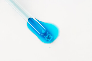 Drop of cosmetics and a pipette on a white background. A product for skin, face or hair care.