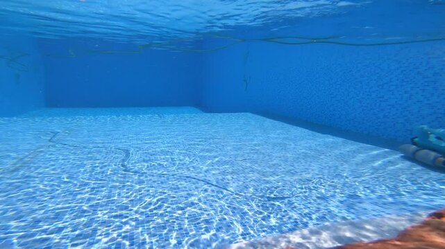 4K video of a pool cleaning device moving steadily across the bottom of a clear swimming pool&mdash;showing routine maintenance, clean water, and smooth equipment operation on a sunny day.