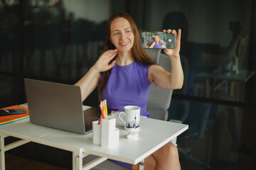 Stylish woman entrepreneur in elegant dress taking selfie at workspace.Modern woman working...