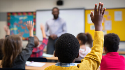 School children raising hands during class with a teacher in front of the blackboard.
