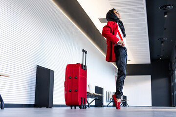 Stylish latin man waiting at the airport with red suit and luggage
