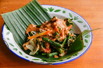 Indonesian vegetable salad with peanut sauce or pecel on vintage enamel plate  lined with banana leaves