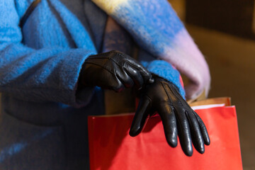 Woman putting on black leather gloves while christmas shopping