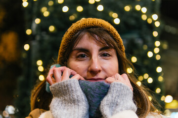 Young woman smiling and keeping warm at christmas market