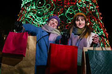 Happy friends showing their Christmas shopping to the camera.